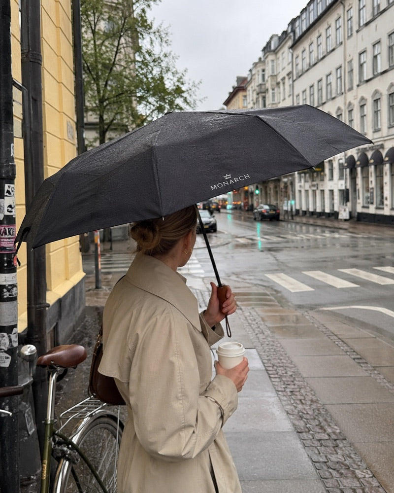Monarch-paraply i regnvejr på københavnsk gade